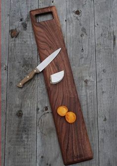 a wooden cutting board with two slices of oranges on it next to a knife