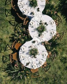 an overhead view of two tables and chairs with white tablecloths on them in the grass