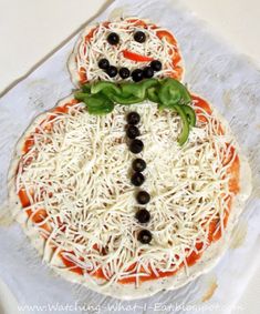 a pizza topped with cheese and black olives in the shape of a snowman