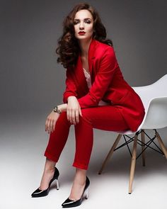 a woman in a red suit sitting on a white chair