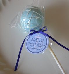 a blue and white lollipop is wrapped in cellophane with a purple ribbon