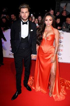 a man and woman standing next to each other on a red carpet at an event