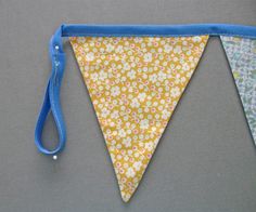 a blue ribbon is hanging from a yellow and white flowered bunting with small flowers on it