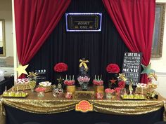 the dessert table is set up with red and gold candy bars, candies, and decorations