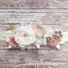 a white headband with pink flowers and gold leaves on top of a wooden surface