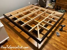 an unfinished bed frame in the middle of a room with hard wood flooring and tools