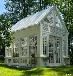 a small white house sitting on top of a lush green field