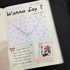 an open book with pink hearts on it and a white envelope in the middle that says wannaa say?