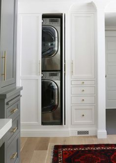 a washer and dryer are in the corner of this white laundry room with built - in cabinets