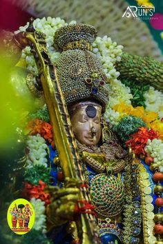 an idol is shown with flowers and other decorations in the background, as well as a gold instrument