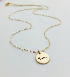 A perfect inspirational gift for runners! This piece features hand-stamped "run." on a circle pendant of your choosing in the font of your choice. The circle measures approx. 1/2 inch and dangles on the chain type and length of your choosing. Wish there was an additional charm added? Another initial? Something else? We love to customize - just send us a message! Details *Pendant: 0.5 in., 14kt gold filled, 16kt gold plated, Sterling Silver, Silver Plated, Rose Gold Filled or Rose Gold Plated *Ha Gift For Runners, Minimal Necklace, Gifts For Runners, Half Marathon, Initial Charm, Circle Pendant, Cross Country, Gold Filled Jewelry, 14kt Gold