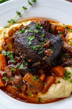 a white plate topped with meat and mashed potatoes covered in gravy, garnished with parsley