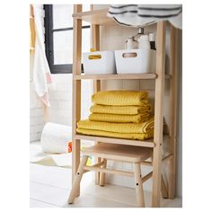 yellow towels are stacked on a shelf in the bathroom