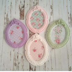 four different colored frames with flowers and laces on the edges, hanging from a white wooden wall