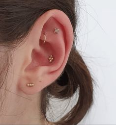 a close up of a person's ear with three piercings on it and one behind the ear