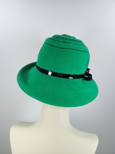 This pretty Kelly green medium brim hat is hand blocked over a vintage hat block and hand sewn. The asymmetrical brim rolls upward in the front and on the left side. Millinery wire is sewed inside of the brim edge to help the hat keep it's shape. The band is a gorgeous vintage patent leather with a matching bow. The top of the hat is hand embroidered in a swirl pattern in black cotton floss. An inner grosgrain headband helps avoid damage from makeup. Gorgeous in every way!+++++++++++++++++++++++ Adjustable Green Fedora Felt Hat, Green Hat Bands For Kentucky Derby, Adjustable Wide Brim Green Felt Hat, Green Fedora For Kentucky Derby, Fitted Hat With Short Brim And Lining, Green Fedora With Curved Brim For Spring, Green Adjustable Felt Hat For Kentucky Derby, Retro Cloche Felt Hat For Winter, Green Short Brim Fedora For Spring