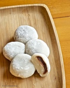 several pastries on a wooden tray with powdered sugar