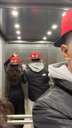 a group of people wearing red hats standing in front of a mirror