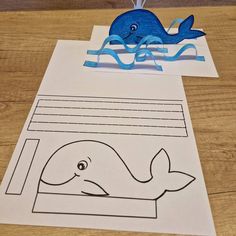 an octopus and whale cut out from paper on top of a piece of paper with blue tape