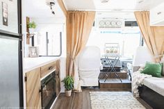 the interior of a camper with curtains open and furniture in place for people to sit