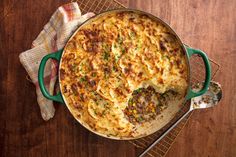 a casserole with meat and cheese in a green dish on a wooden table