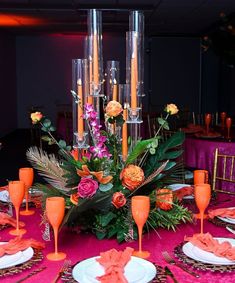 the table is set with orange and pink flowers, silverware, and champagne flutes