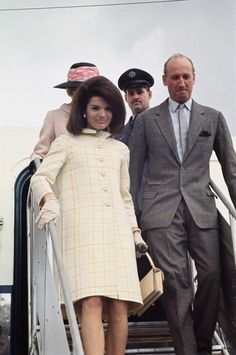 two men and a woman are walking up the stairs to board an air plane together