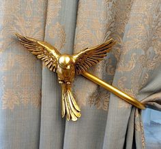 a gold bird curtain tie bar on top of a drapes in a living room