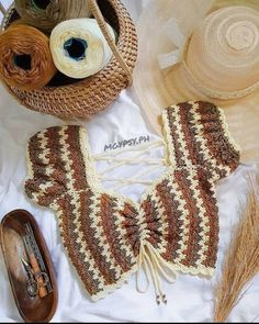 a crocheted top and hat on a bed with other items in the background