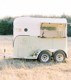 an old trailer is parked in the middle of a field