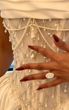 a woman's hand on the back of a wedding dress with pearls and diamonds