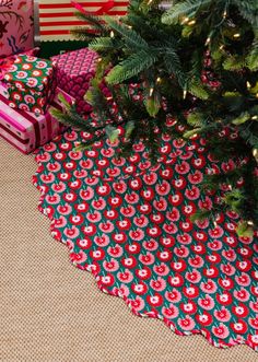 presents under a christmas tree with red and green wrapping on the ground next to it