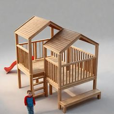 a small child standing next to a wooden toy house with a slide and ladder in the background