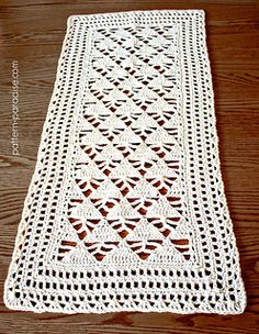 a white crocheted table runner sitting on top of a wooden floor