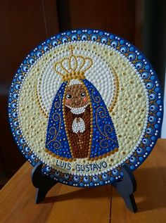 a blue and white plate with an image of the virgin mary in gold on it