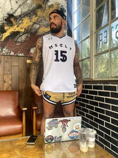 a man with tattoos standing in front of a table