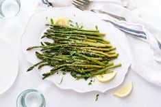 asparagus on a white plate with lemon wedges