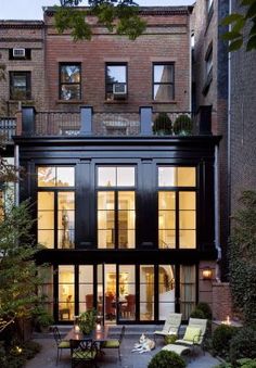 an apartment building with lots of windows and plants in the courtyard, as well as patio furniture