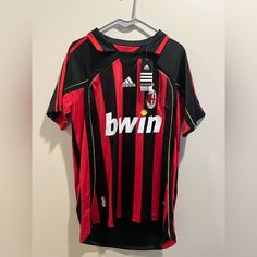 a red and black soccer jersey hanging on a hanger