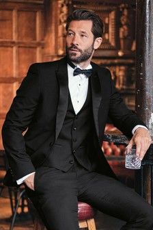 a man in a tuxedo sitting on a chair