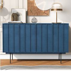 a blue sideboard sitting on top of a hard wood floor next to a lamp