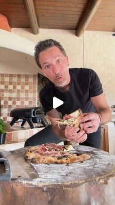 a man standing in front of a pizza on top of a table