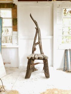 a wooden bench made out of branches in a room with white walls and wood flooring