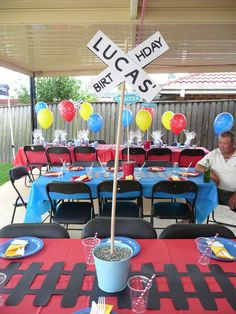 a man sitting at a table with balloons and plates on it