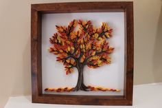 a wooden frame with an autumn tree cut out of paper in the shape of leaves