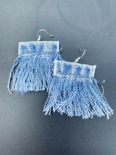 two pairs of earrings with fringes hanging from the end of each earring, on a black surface