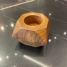 a wooden bowl sitting on top of a counter next to a black table with white dots