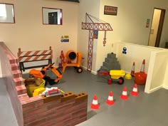 a play room with construction equipment on the floor and orange traffic cones in front of it