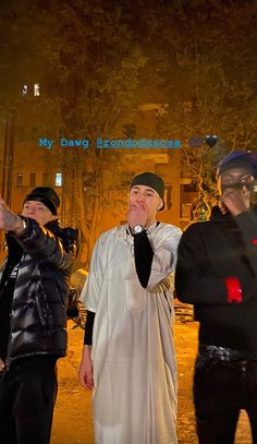 three men standing in the street talking on their cell phones