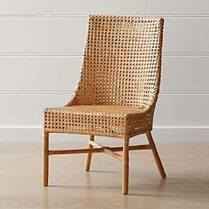 a wicker chair sitting on top of a hard wood floor next to a white wall